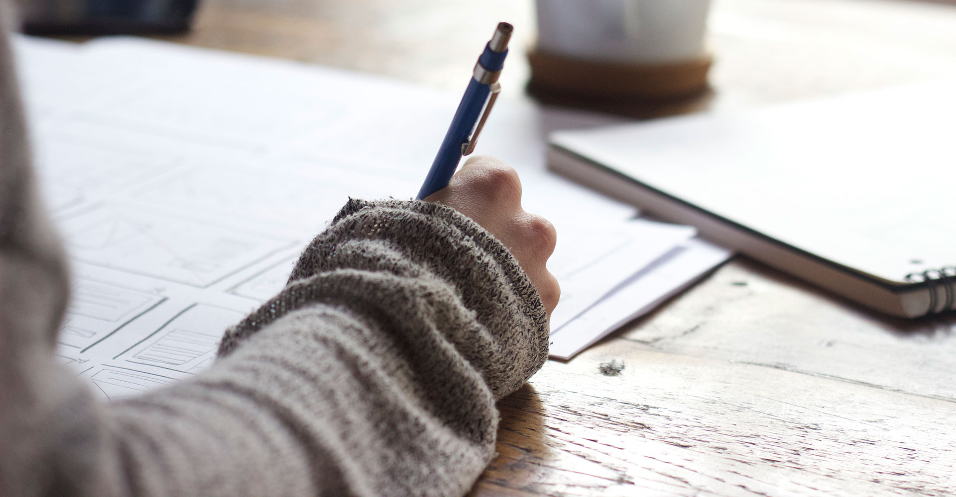 Personne dessinant des interfaces à côté d'un carnet ouvert