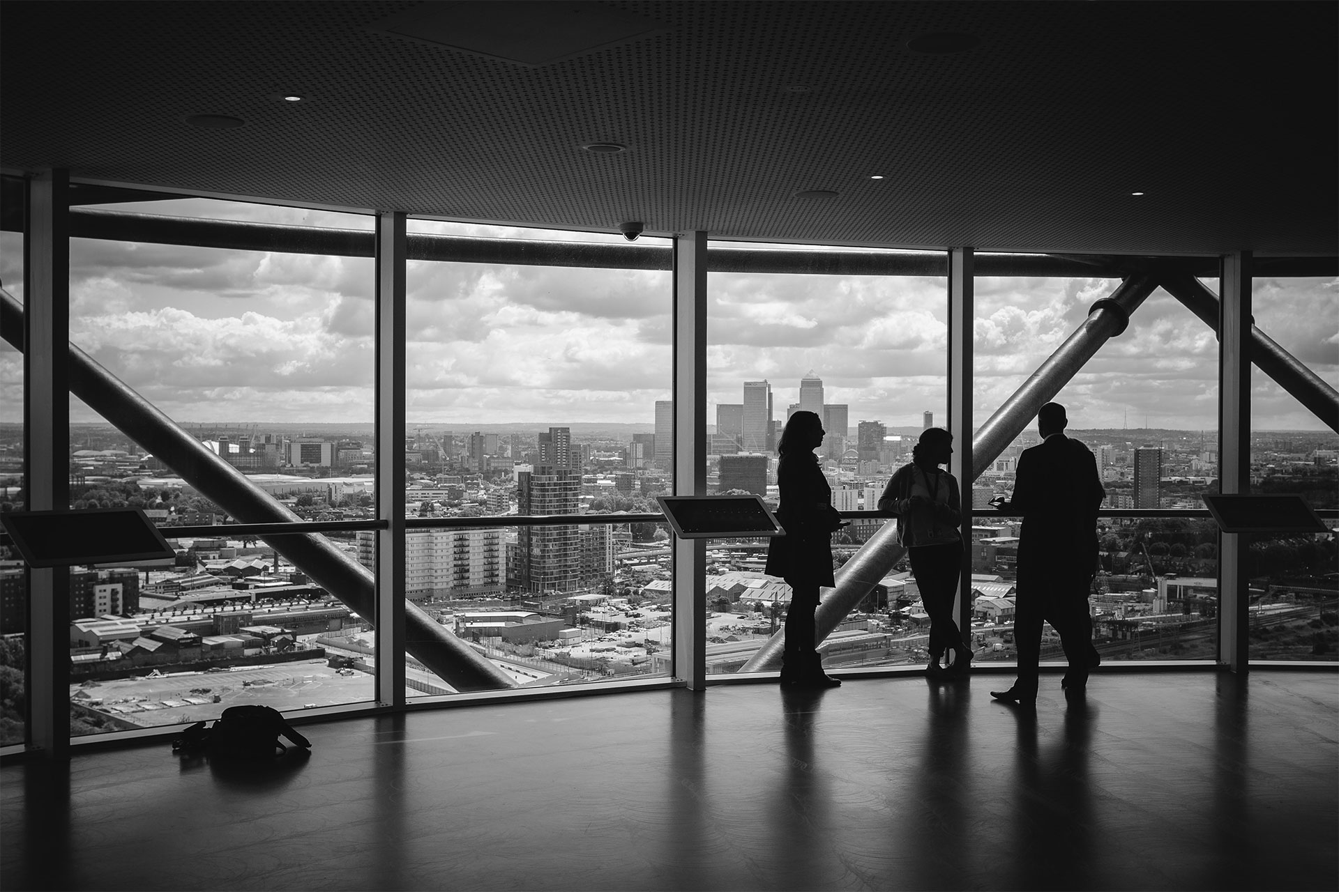 Three people standing by windows overlooking a city